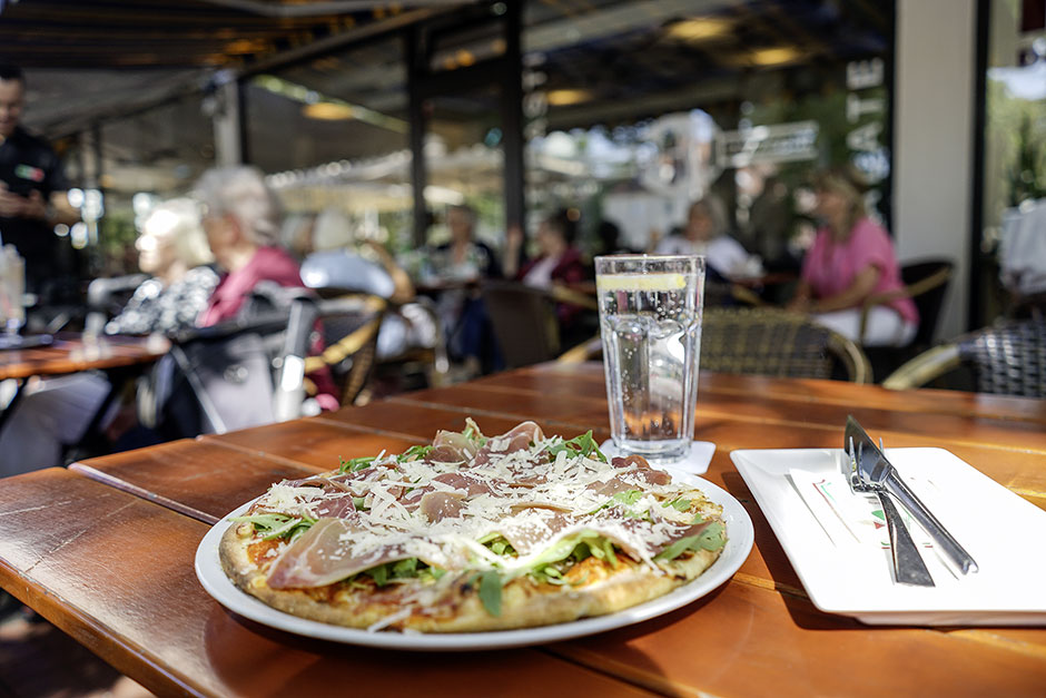 Pizza mit Parmaschinken, Rucola und Parmesan auf der Terrasse des Roni